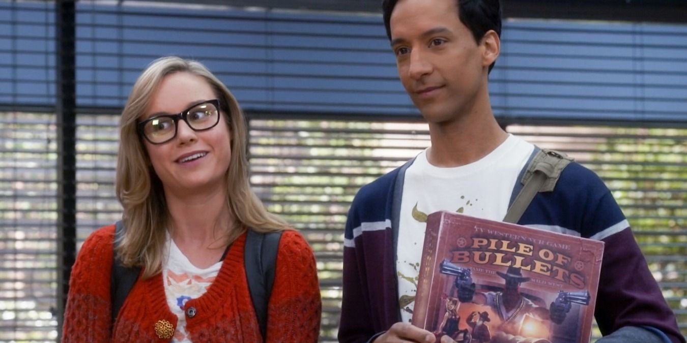 Rachel and Abed standing in the study room, holding a board game