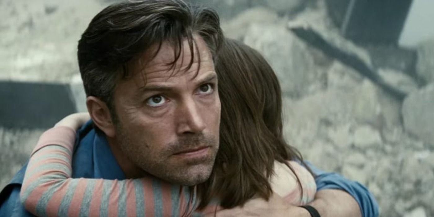 Bruce Wayne hugging a child as the city falls around them in Batman v Superman