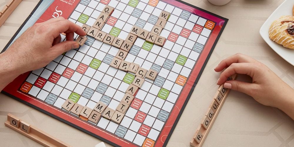 Image of Scrabble board with two hands and some words played.
