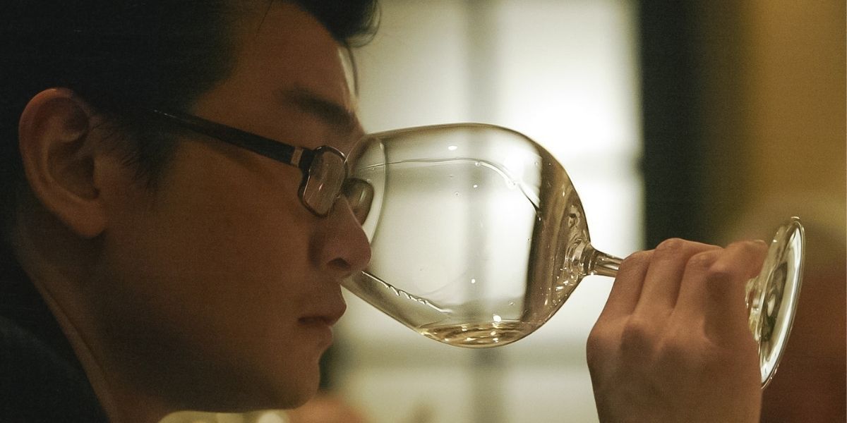 A man looks inside a glass of wine in Sour Grapes