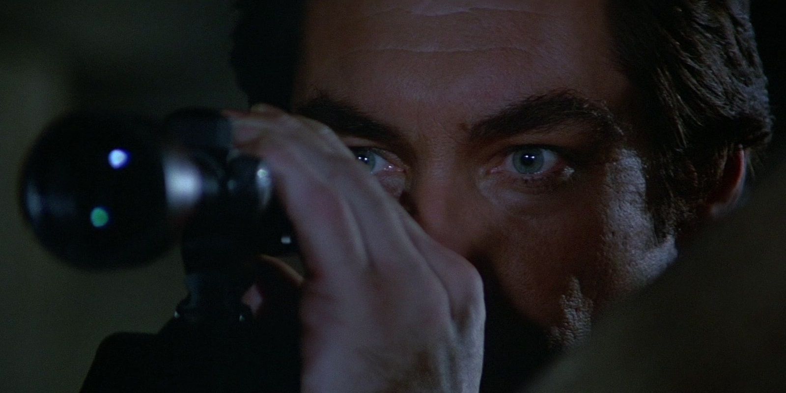 Timothy Dalton as Bond looking through a scope