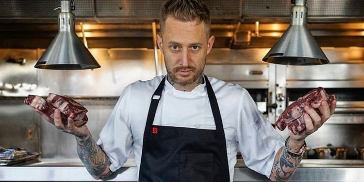 Michael Voltaggio on his kitchen holding raw steaks on each hand
