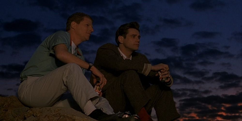 Truman and a fake friend sitting on the beach in The Truman Show