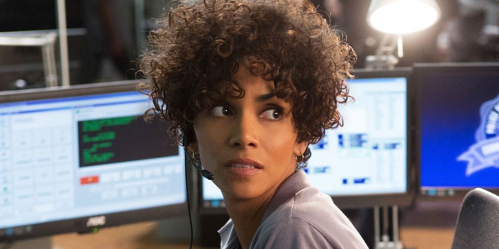Halle Berry wearing a headset sitting at computers, looking behind her worriedly in The Call