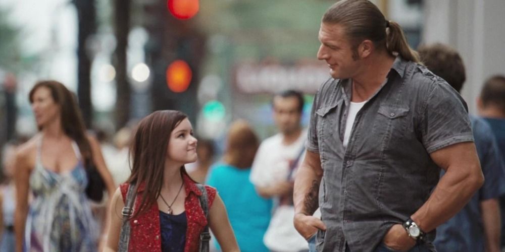 Paul &quot;Triple H&quot; Levesque and little girl on the street smiling at each other in The Chaperone.
