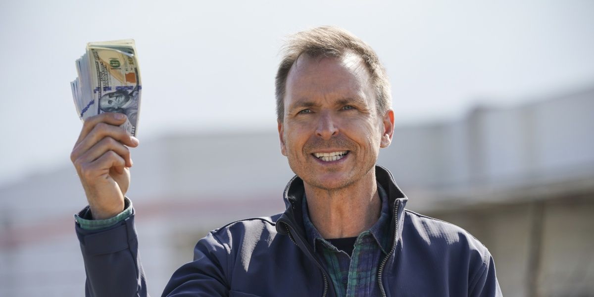 Phil Keoghan holding a wad of cash