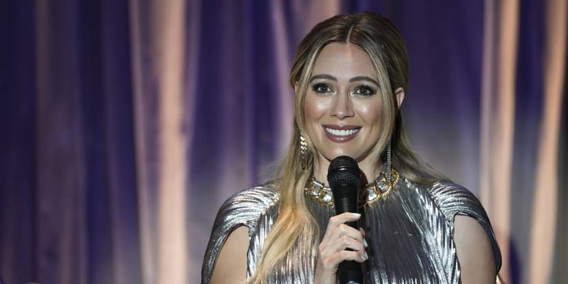 Kelsey standing behind a microphone on Younger