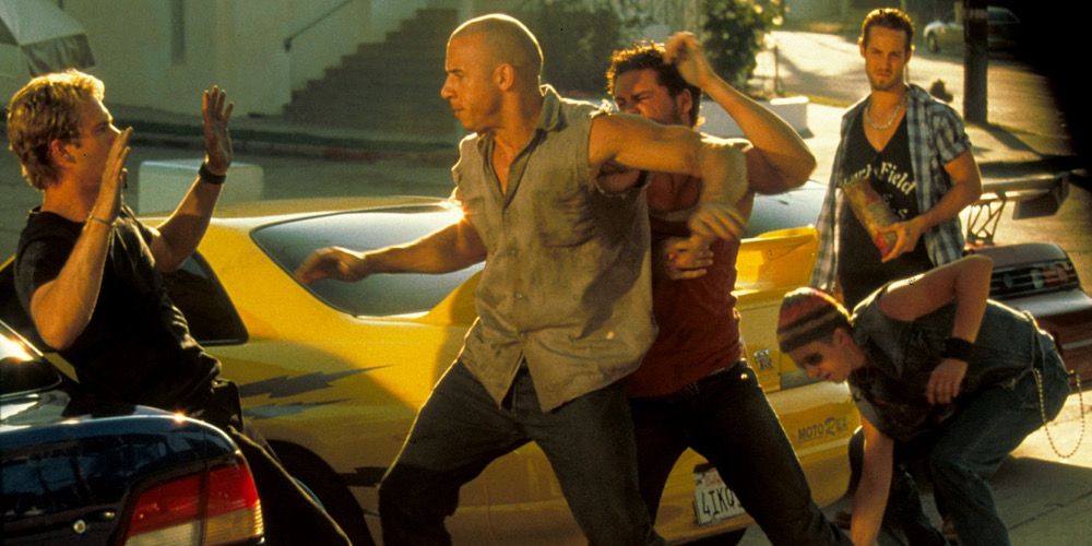Dom threatens Brian as he’s leaning against a car in The Fast and the Furious