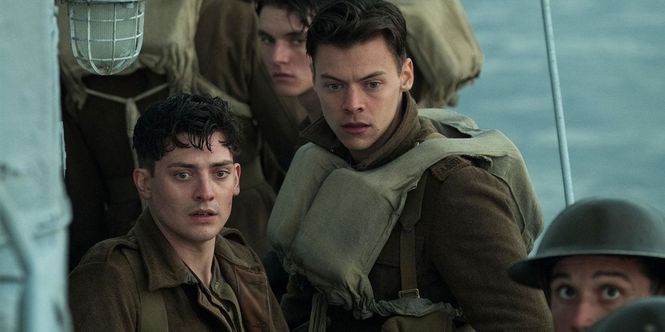 Alex standing with the other men on the boat, looking shocked in Dunkirk