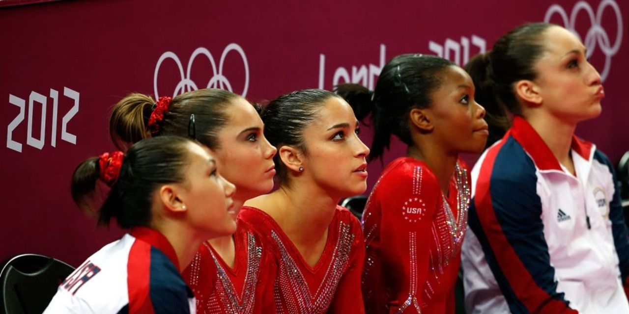 An image of the USA gymnast team sitting down on a bench in At The Heart Of Gold