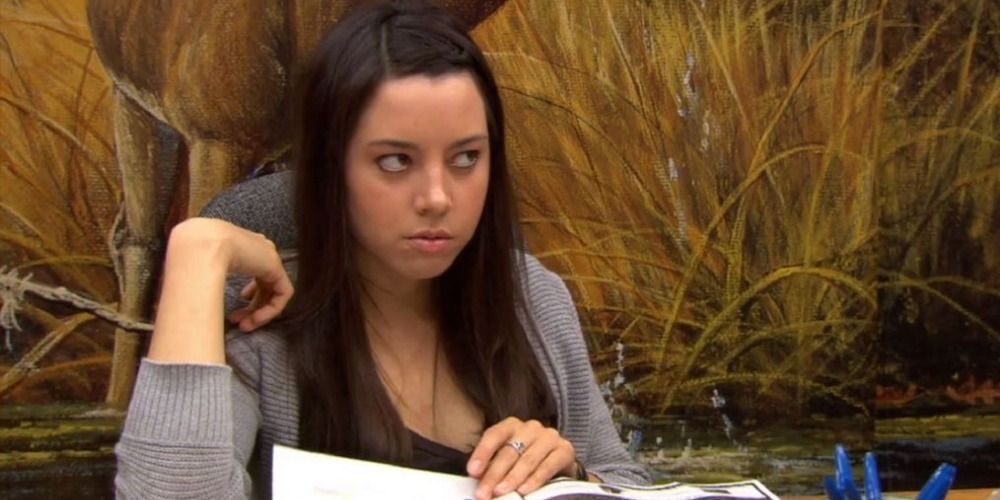 April from Parks and Recreation sat down, holding a book, looking annoyed