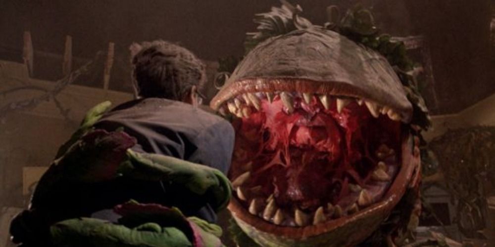 Audrey 2 from Little Shop of Horrors holding up Seymour in his vines, about to eat him