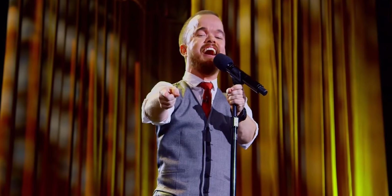 Brad Williams in Fun Size special pointing to an audience member and laughing on stage.