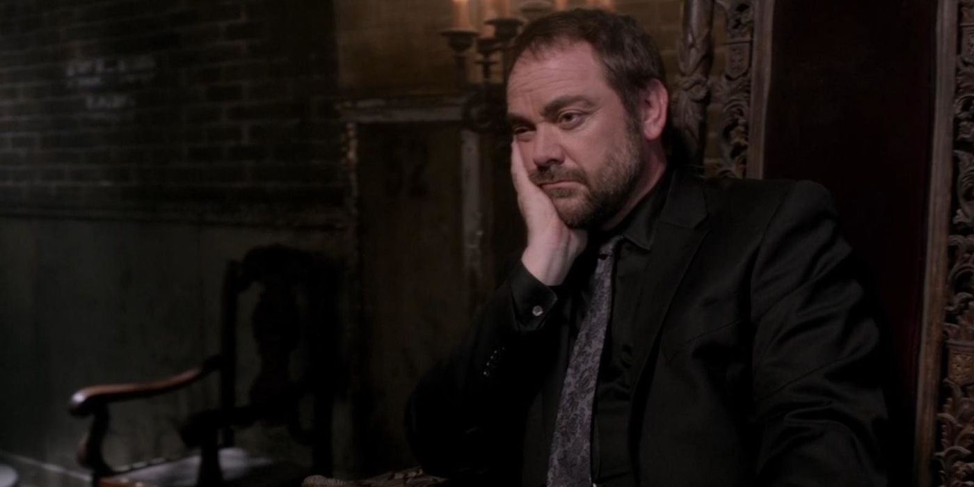 Crowley sitting in a chair in Supernatural.