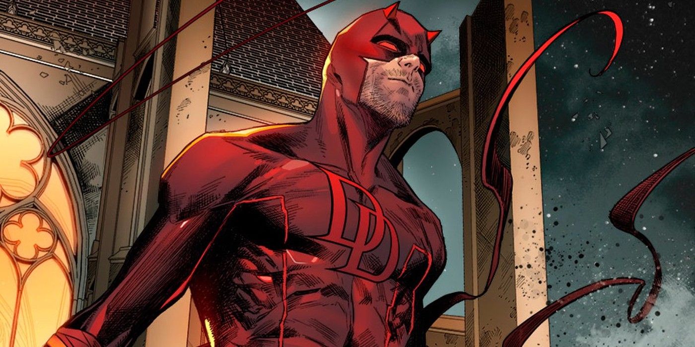 Daredevil standing atop a building in his red suit.