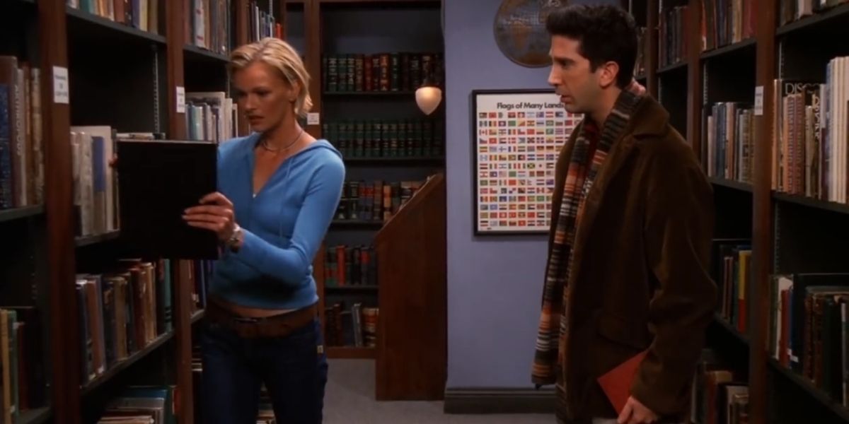 Ross and a female student talk in the library in Friends