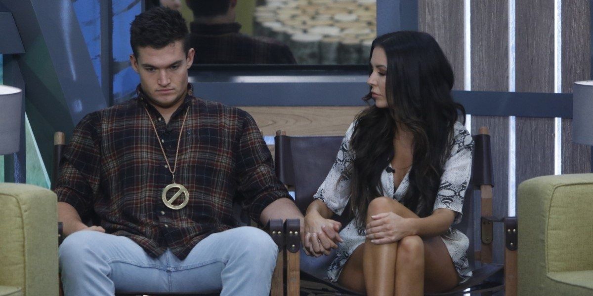 Jackson and Holly from Big Brother sitting on the block looking solemn and holding hands.