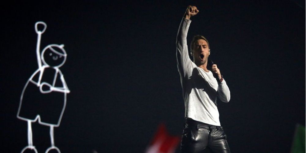 Mäns Zelmerlow performing his song Heroes at Eurovision, holding his fist in the air in front of an animated child