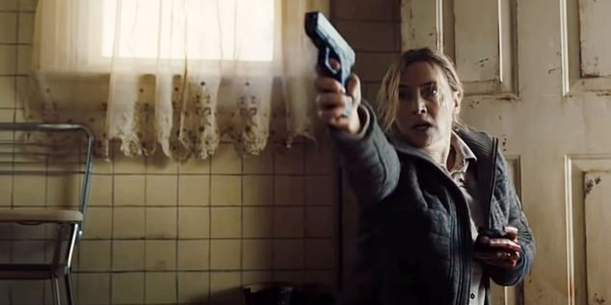 Mare Sheehan (Kate Winslet) with her gun drawn in Wayne Pott's house in Mare of Easttown