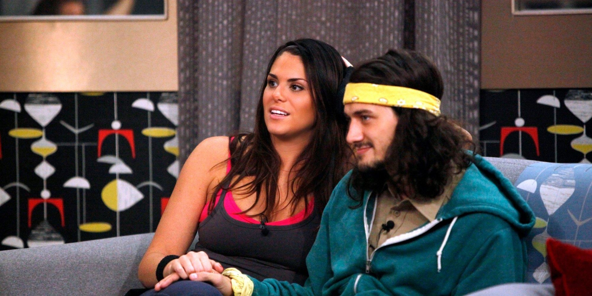 McCrae and Amanda sitting on the couch holding hands and smiling off camera.