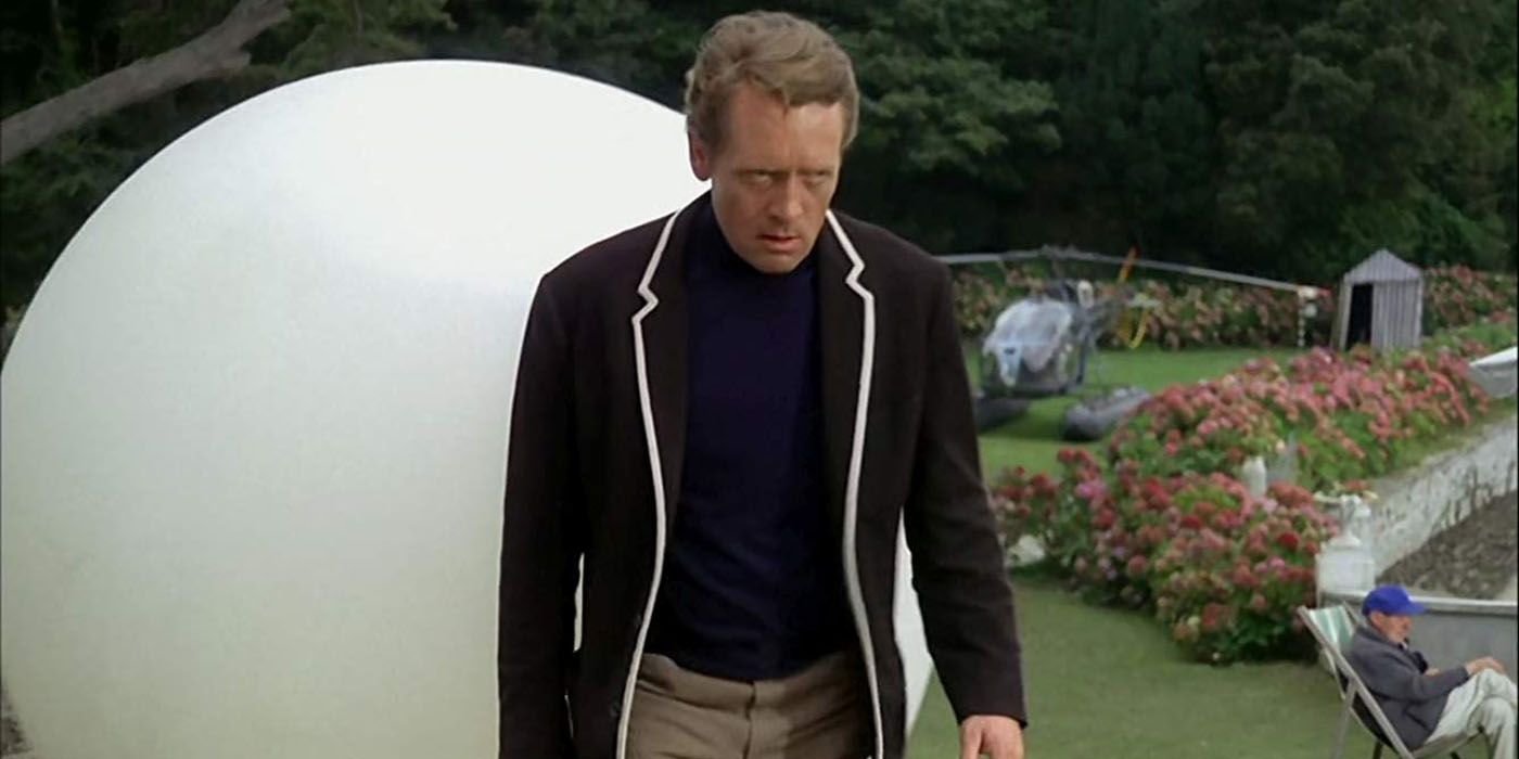 Nomor Enam dari acara sci-fi The Prisoner berdiri di luar dan tampak posesif.