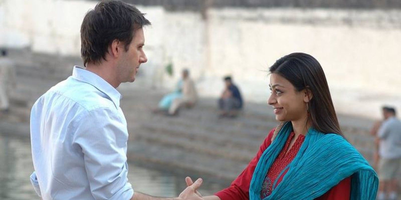 A man and woman shake hands on a beach in Outsourced