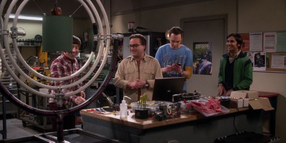 Raj, Howard, Sheldon and Raj all looking at the model on the table in The Big Bang Theory