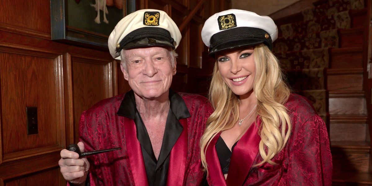 Hugh Hefner and one of his girlfriends posing together in matching robes and captain hats
