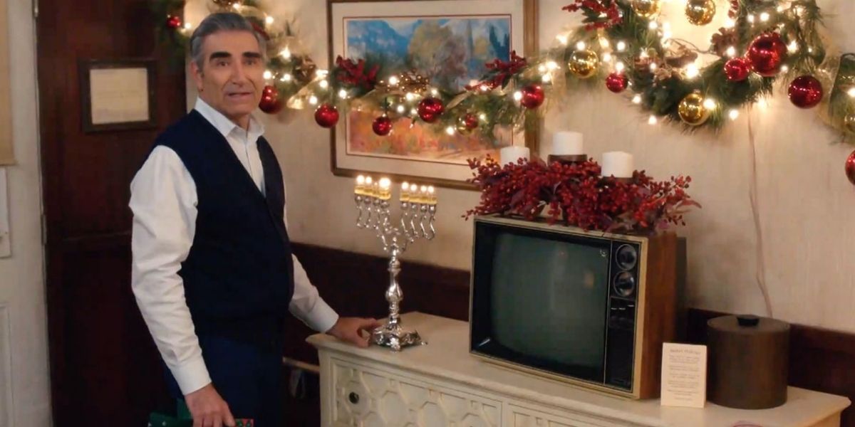 Johnny placing a Menorah in the Christmas decorated motel room