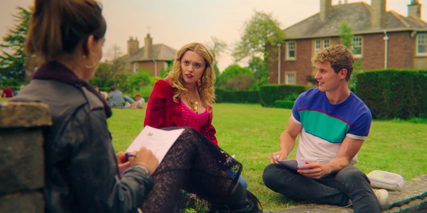 Aimee from Sex Education sits on the grass with Steve and Maeve