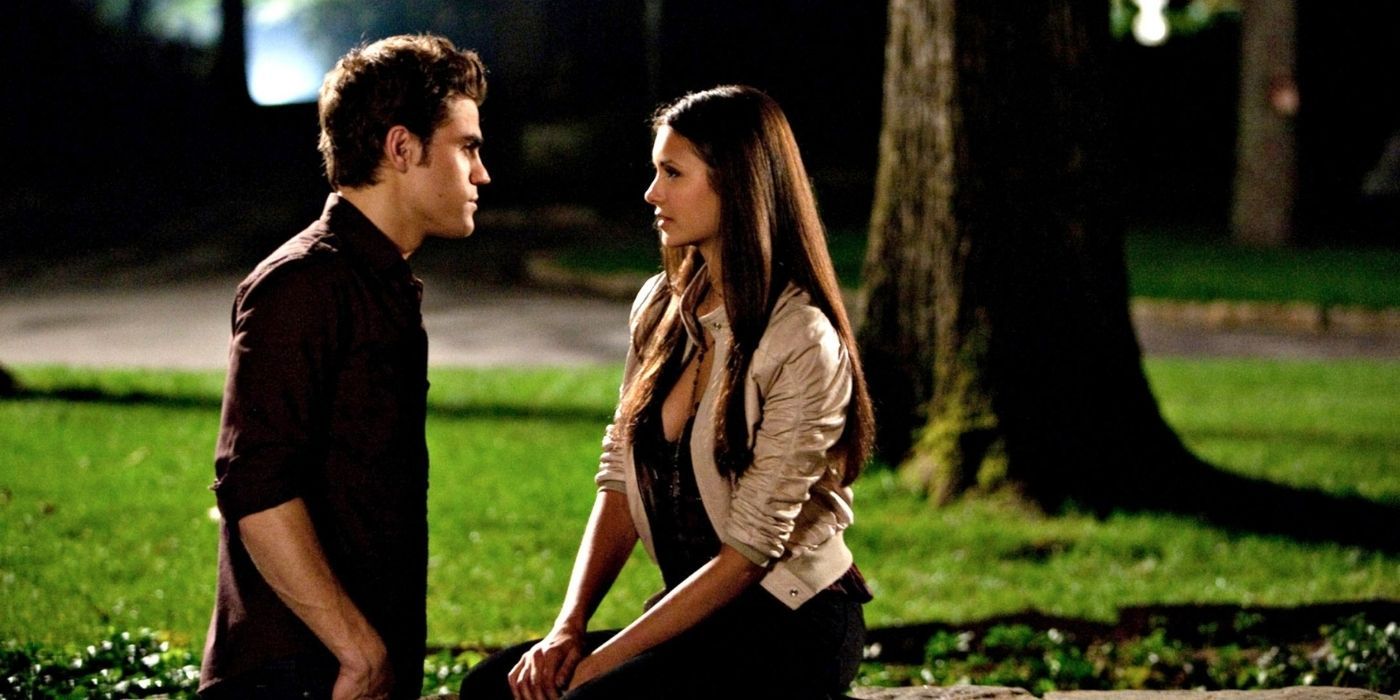 Stefan talks to Elena, who is seated on a rock, in an image from season 1 of The Vampire Diaries.