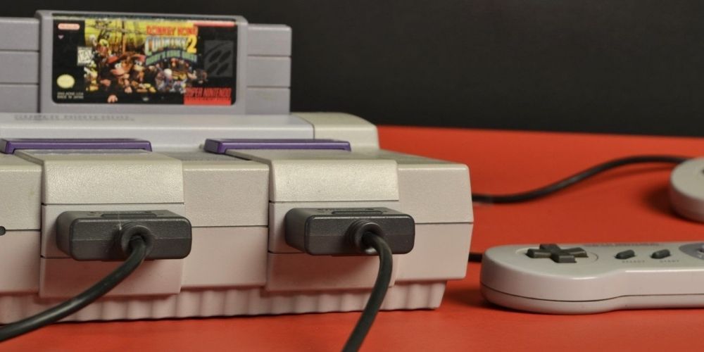 Image of a Super Nintendo (SNES) and a Donkey Kong cartridge on an orange table.