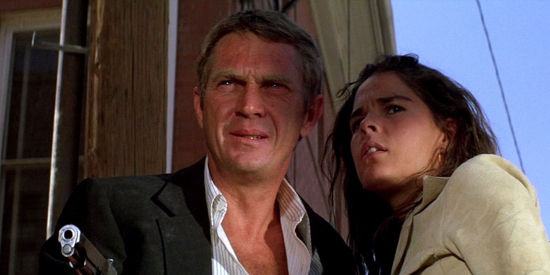Steve McQueen holding a gun with Ali McGraw looking off camera in The Getaway