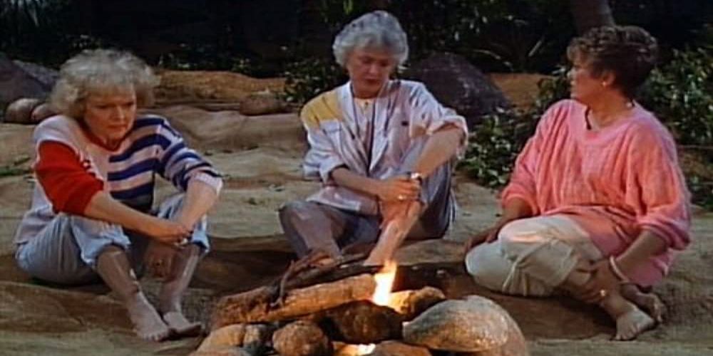Rose, Dorothy, and Blanche sit by a fire on a deserted island on The Golden Girls.