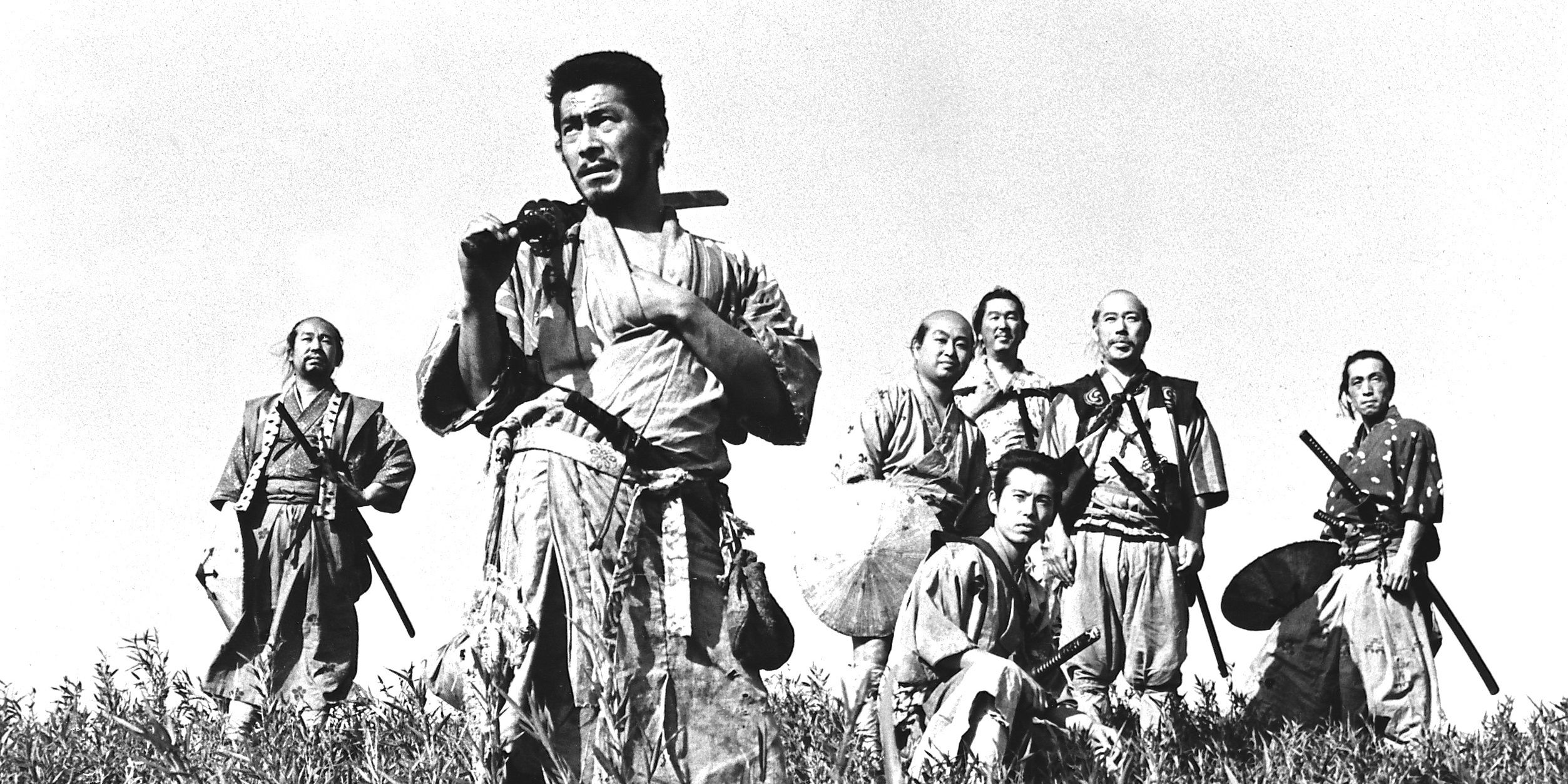 Toshiro Mifune, Takashi Shimura, and the rest of the main cast of Seven Samurai standing in a field