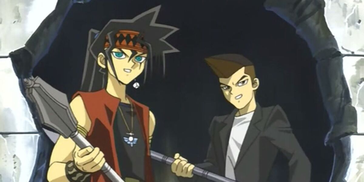 Tristan and Duke standing in a hole in the wall, wielding weapons in the Yu-Gi-Oh! anime.