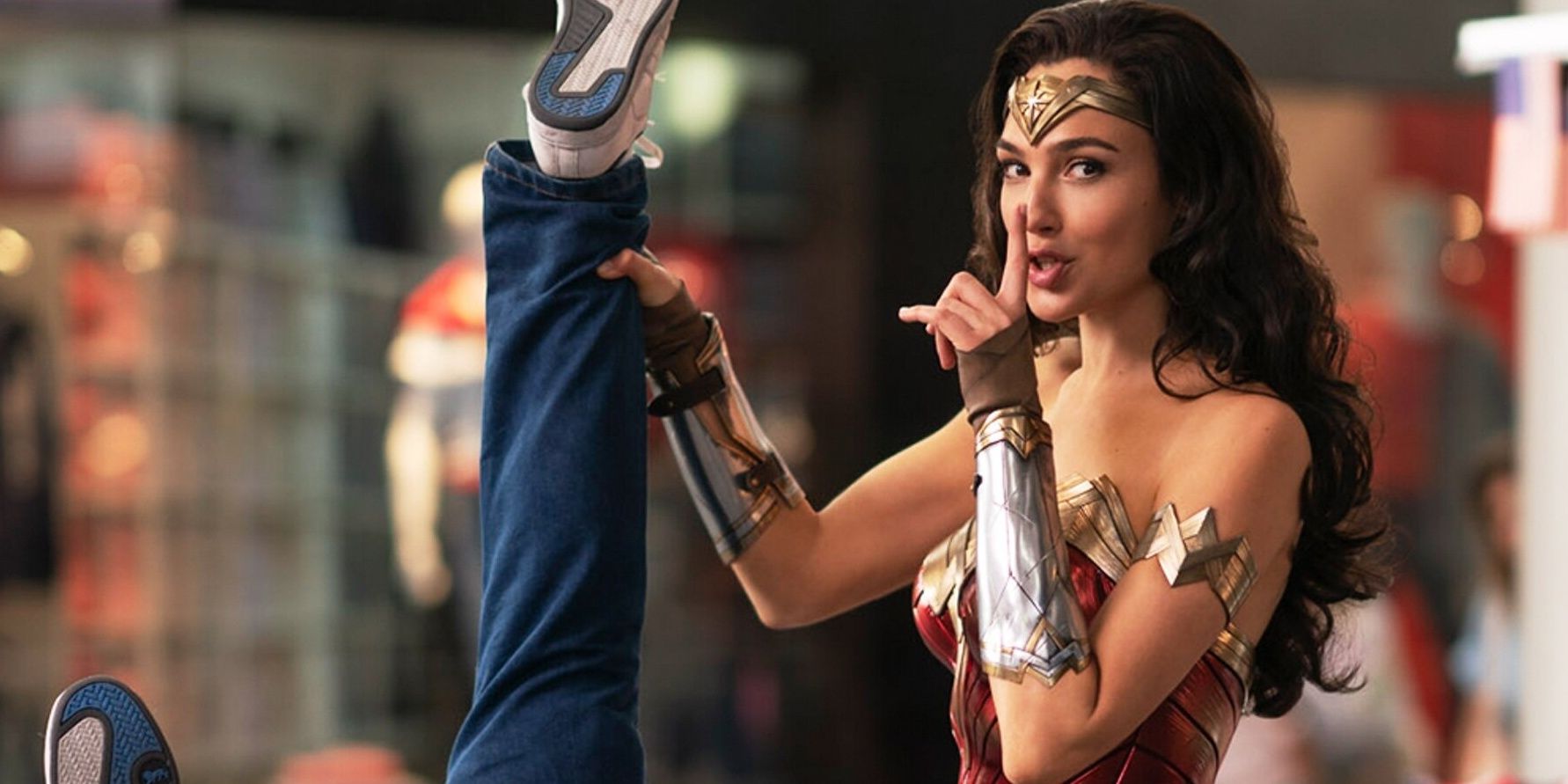Wonder Woman does the Shush gesture while holding a prisoner in Wonder Woman 1984
