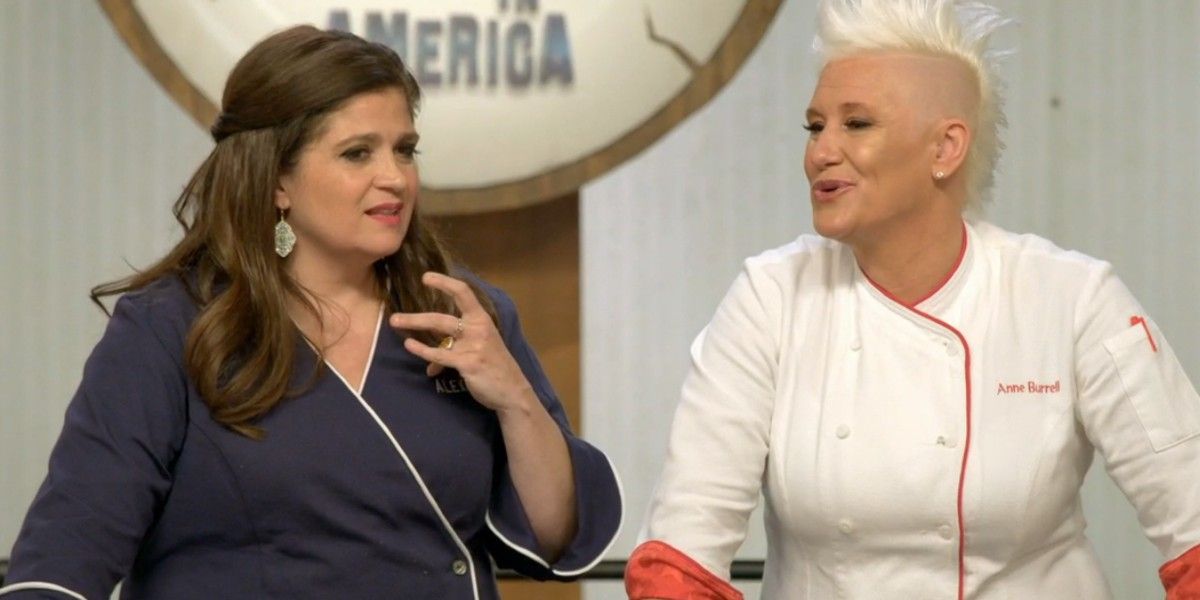 Alex Guarnaschelli and Anne Burrell looking at each other and wearing chef jackets on Food Network's 'Worst Cooks in America.' 