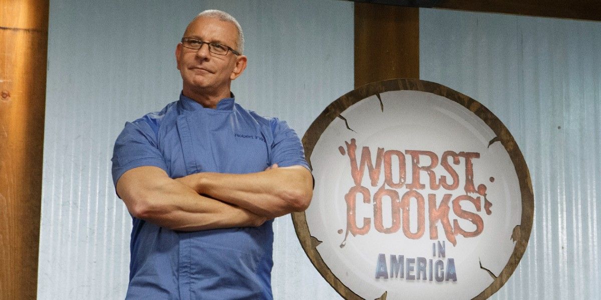 Robert Irvine in a blue shirt standing with his arms crossed.