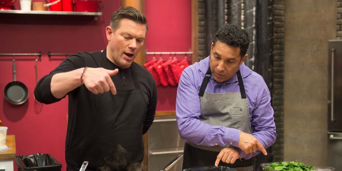Tyler Florence in a black shirt coaching a recruit on Food Network's 'Worst Cooks in America.'