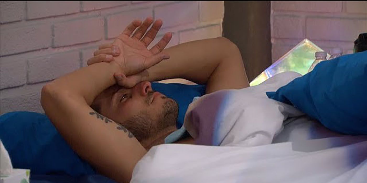 Cody Calafiore lying in bed with his hands at his face, looking sad.