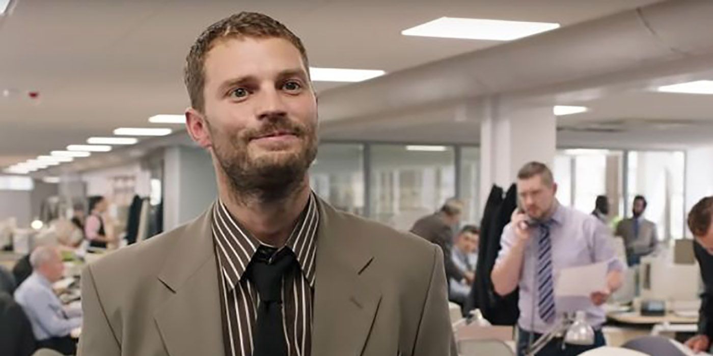 Jamie Dornan with a closed-lip smile, wearing a tan suit.