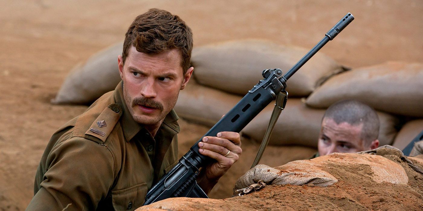Jamie Dornan on the ground with a gun, with a moustache.