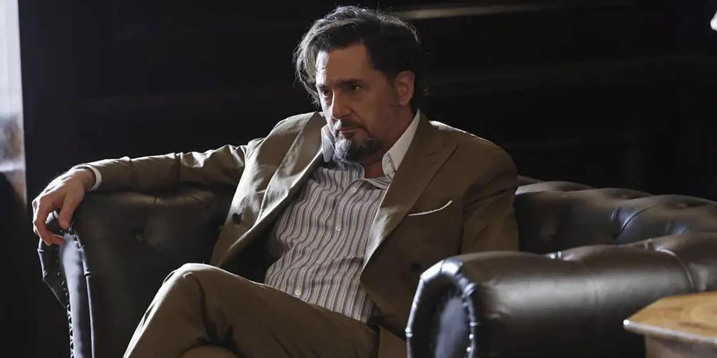 Neville Towndsend slouched down in a chair, wearing a suit on The Blacklist.