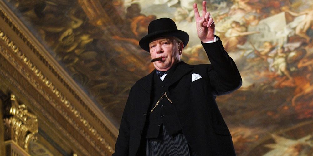 Winston Churchill makes a peace sign with his hands in The Gathering Storm