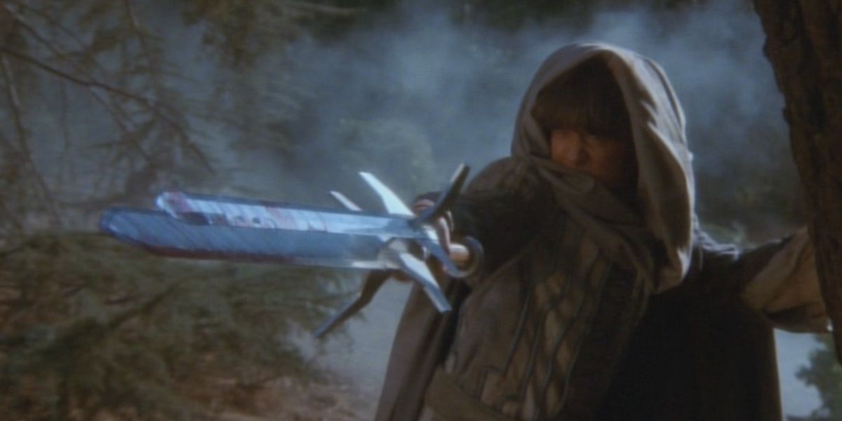 A man holding a triple bladed sword in a still from The Sword and The Sorcerer 