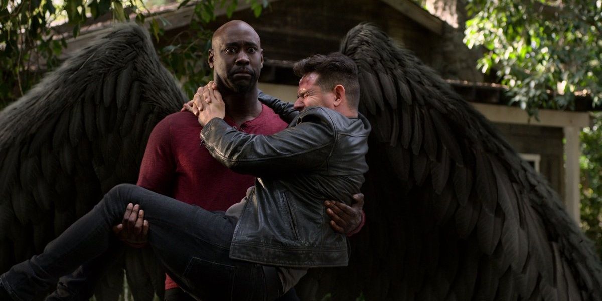 Amenadiel holding an injured man with his wings stretched out in Lucifer
