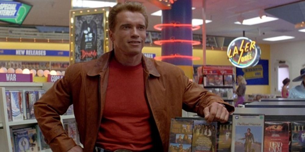 Arnold Schwarzenegger in The Last Action Hero, wearing a brown leather jacket, in a video store