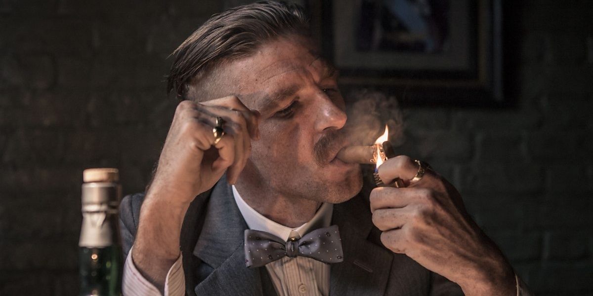 Arthur Shelby smokes a cigar as a he dares a woman to shoot him in Peaky Blinders