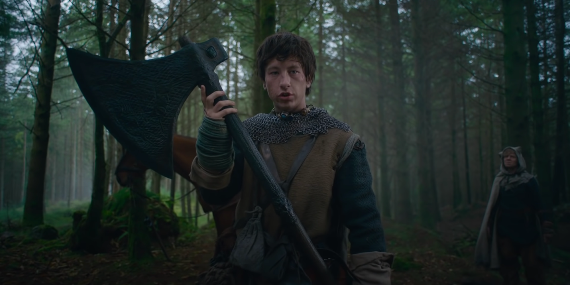 Barry Keoghan as the Scavenger in the Woods with an Axe in The Green Knight